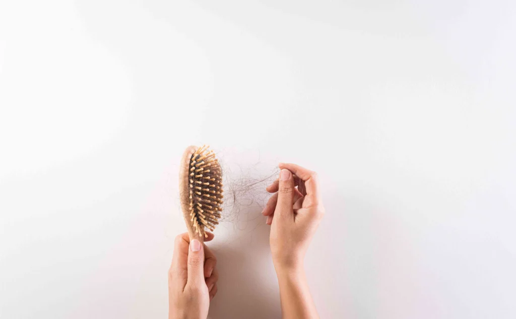 A wooden hairbrush with a large amount of lost hair | Hair Loss Treatment in Austin, TX with Glo Medspa